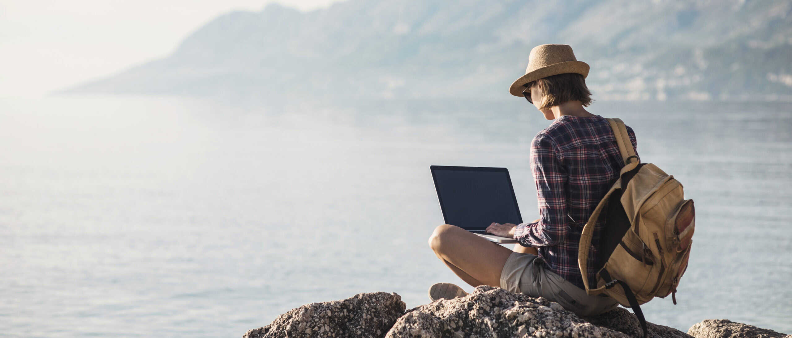 young woman learning on laptop at a lake